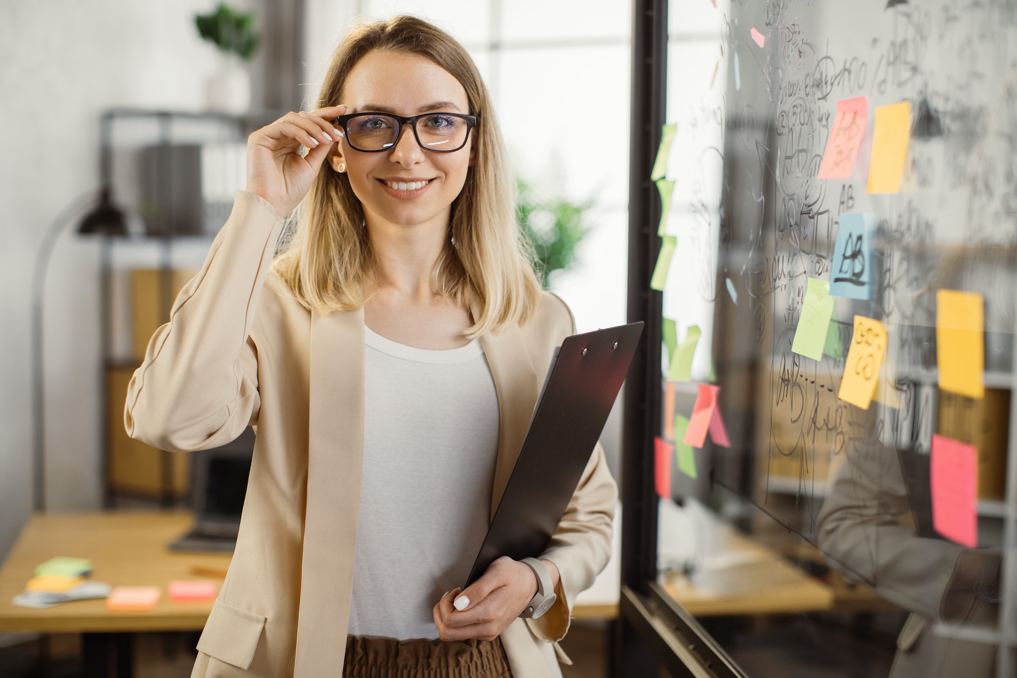 Business lady holding clipboard and smiling at office