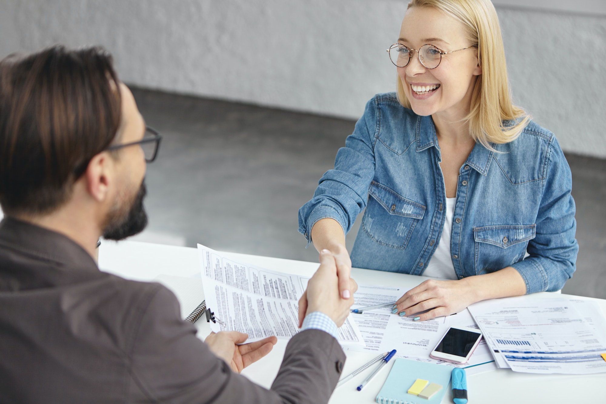 Bussines agreement and regulations concept. Glad blonde successful female and male shake hands as si